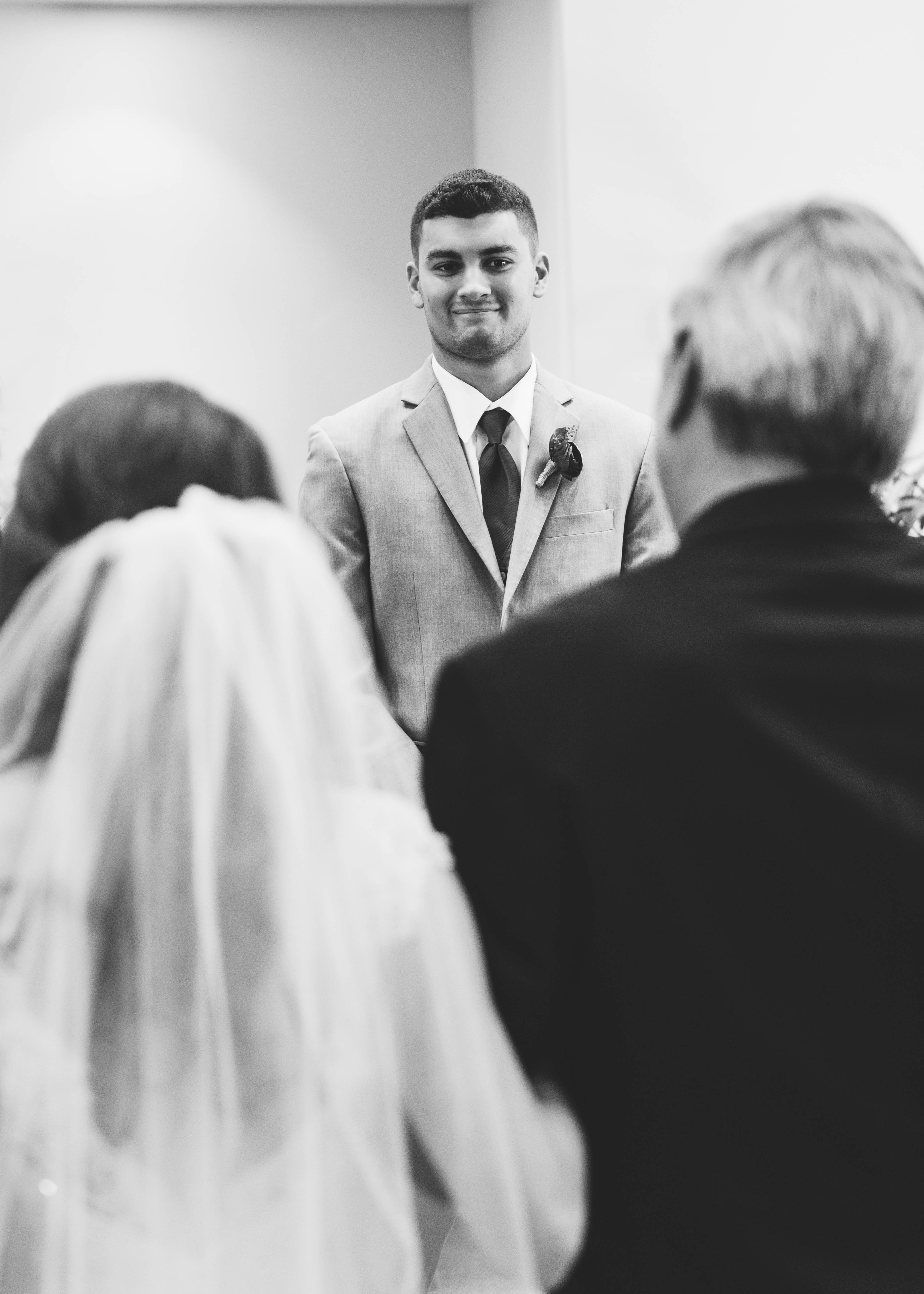 groom smiles as bride and her father walk down the aisle