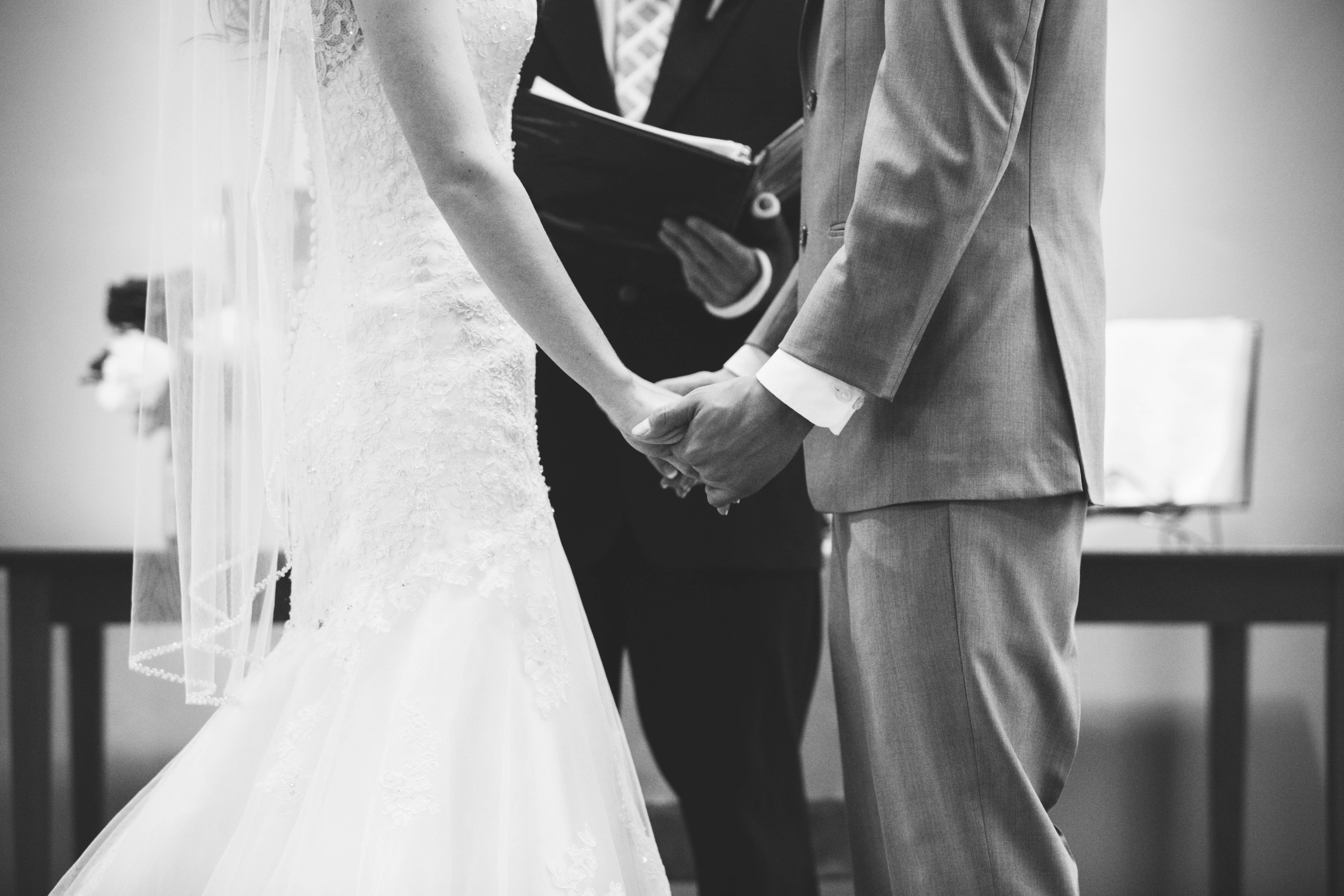 closeup of bride and groom holding hands at the altar