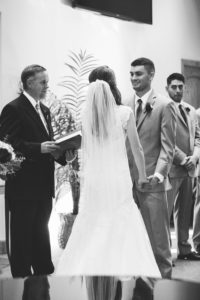groom smiles at his bride as they stand at the altar