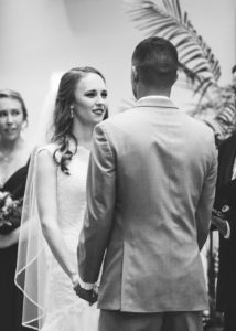 bride smiles at her groom while they stand at the altar
