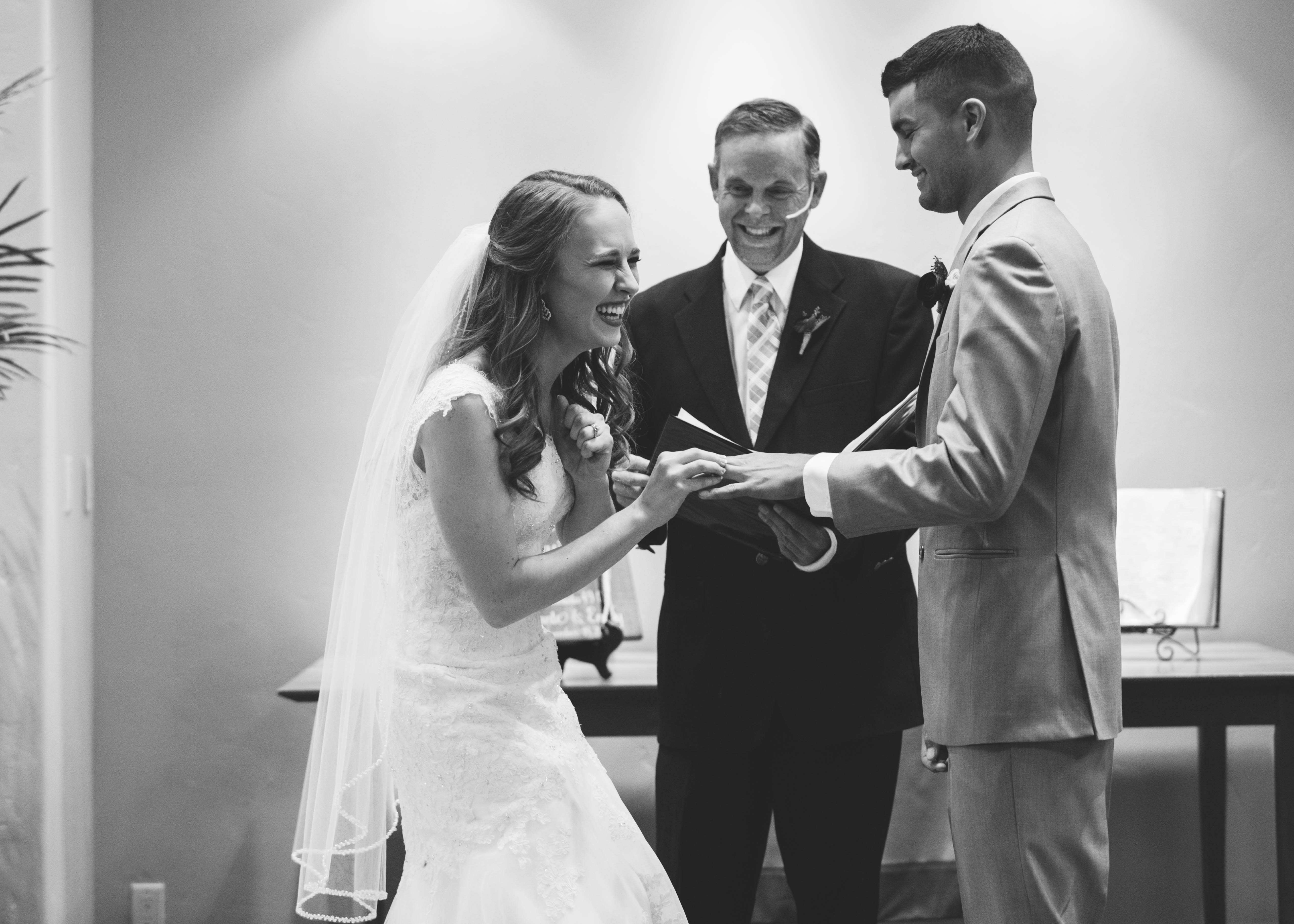 bride laughs as she places ring on groom's finger