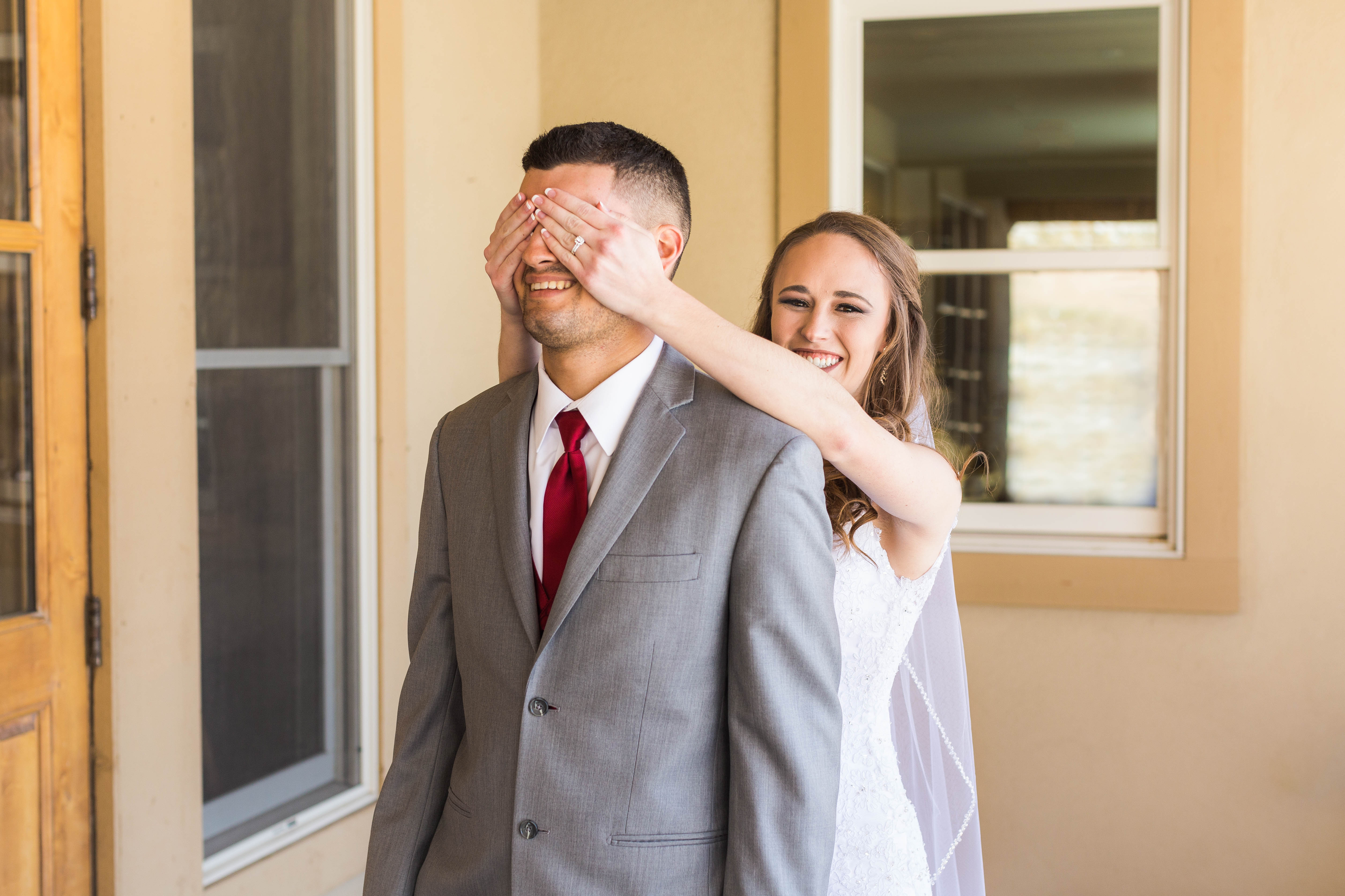 Bride giggles as she covers groom's eyes during first look