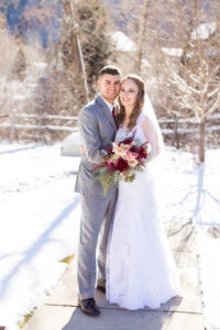 bride and groom stand in the snow and smile