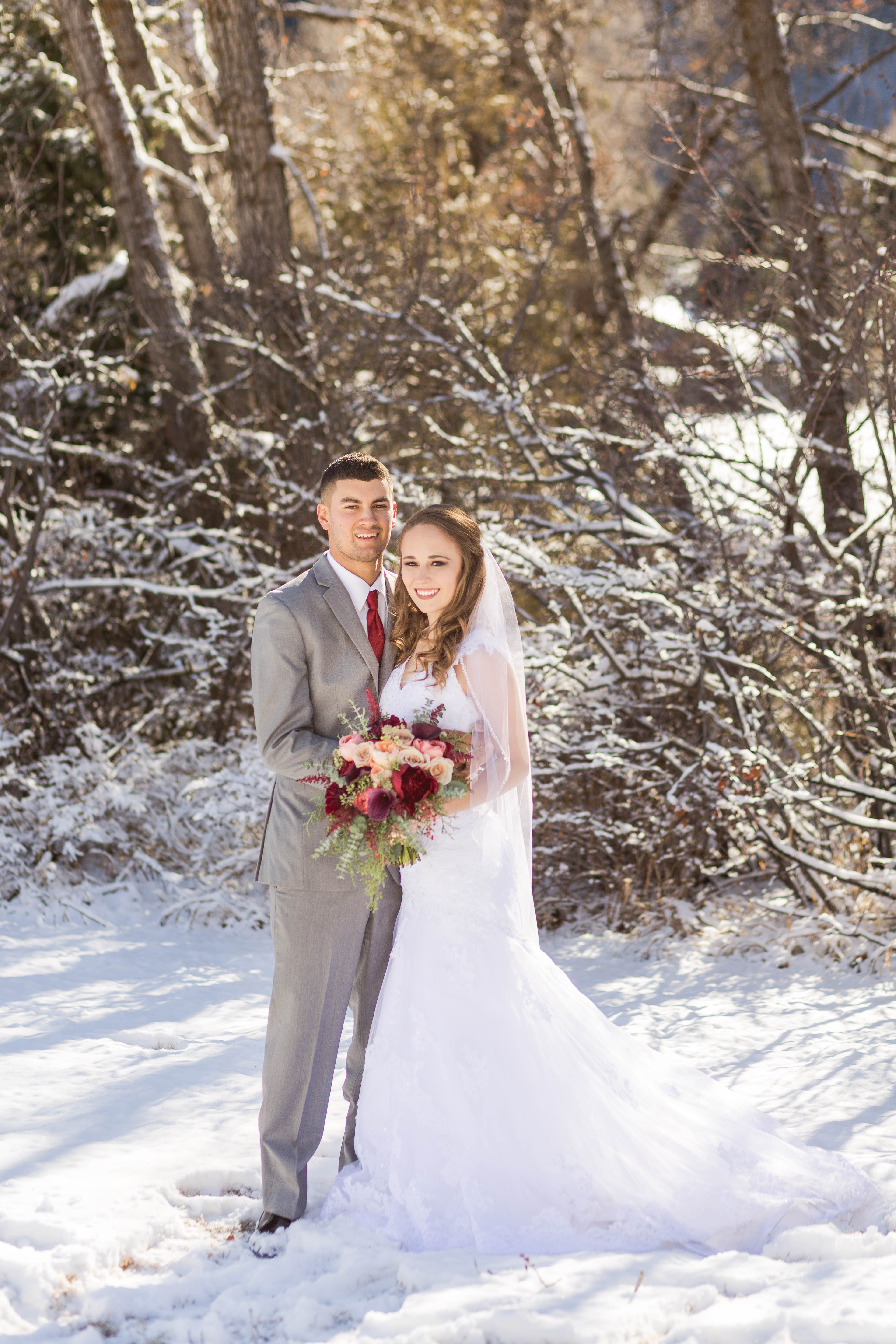 bride and groom embrace each other in the snow