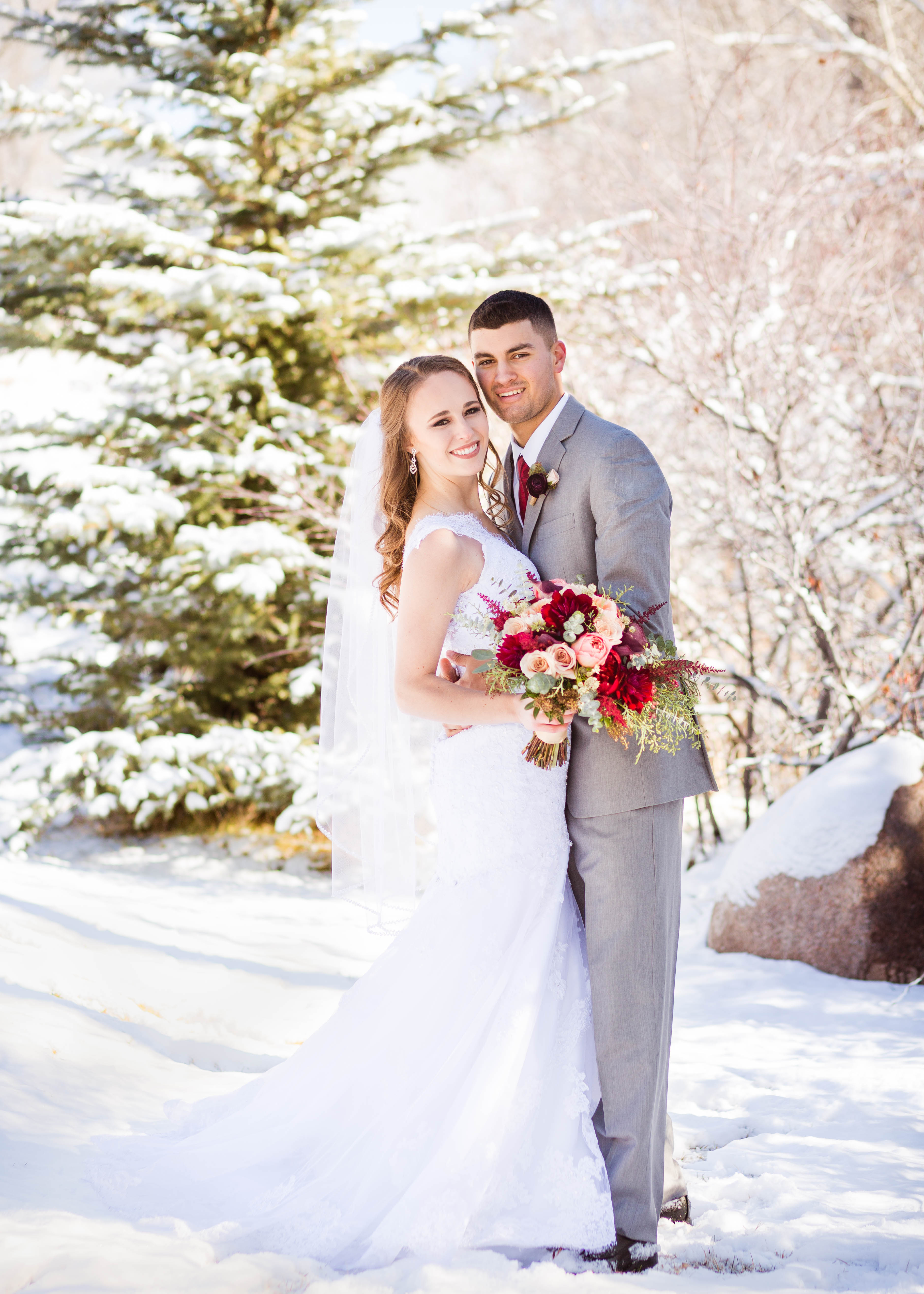 bride and groom embrace in a snowy backdrop