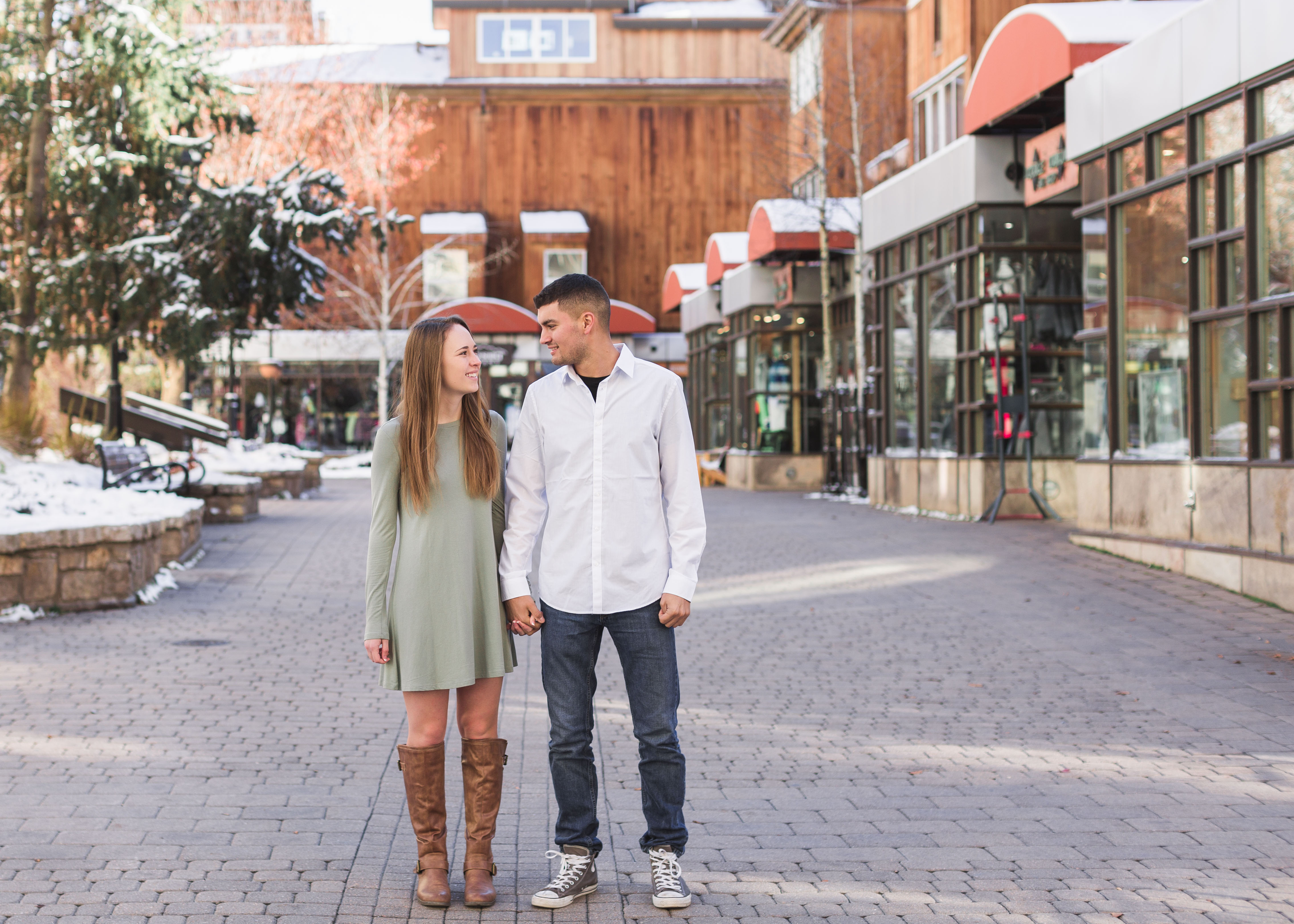 couple stand side by side and look at each other in front of shops in Vail Village