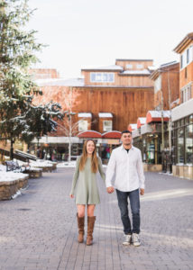 Couple holds hands and walks down brick street in Vail Village