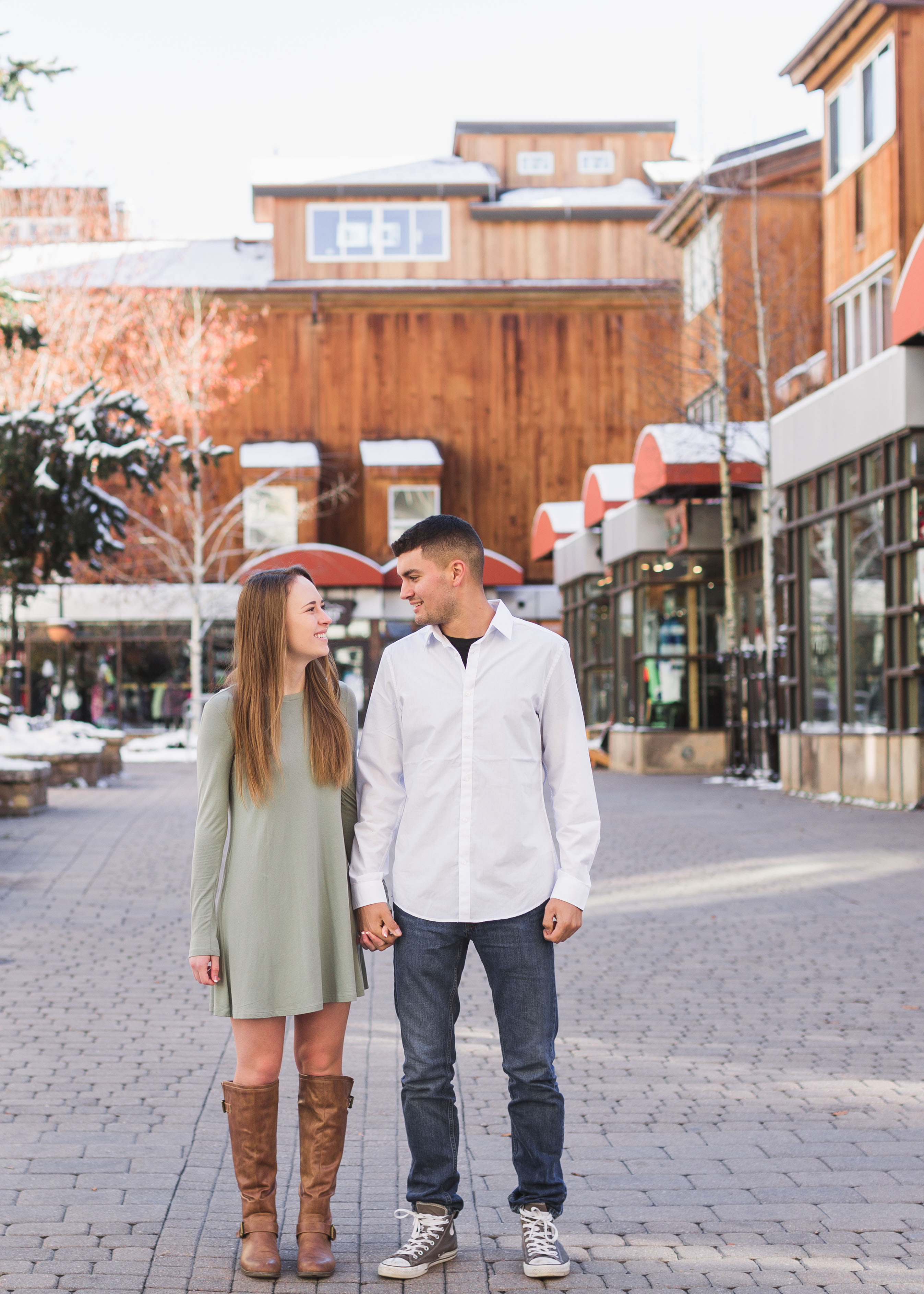 couple standing side by side and smile at each other in front of shops in Vail Village