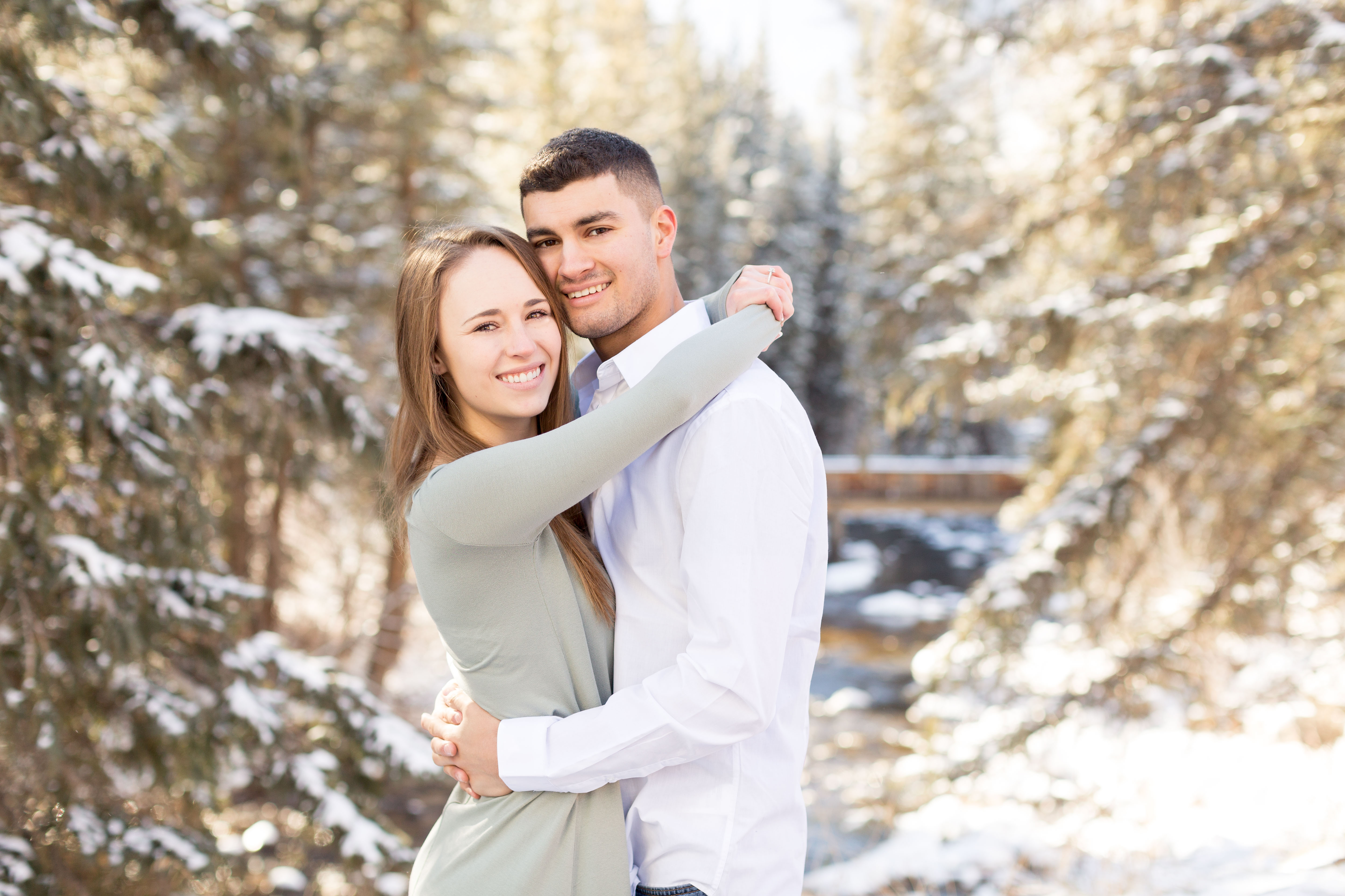 Couple wrap their arms around each other in the snowy forrest at Vail Ski Resort