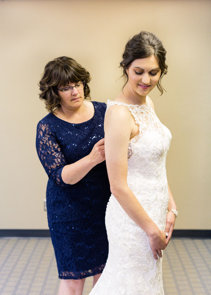 Mom helps her daughter into her wedding dress