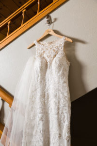close up of white lace wedding dress hanging in a stairwell