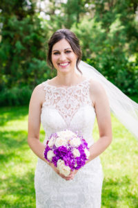 Bride smiling holding her purple and white bouquet