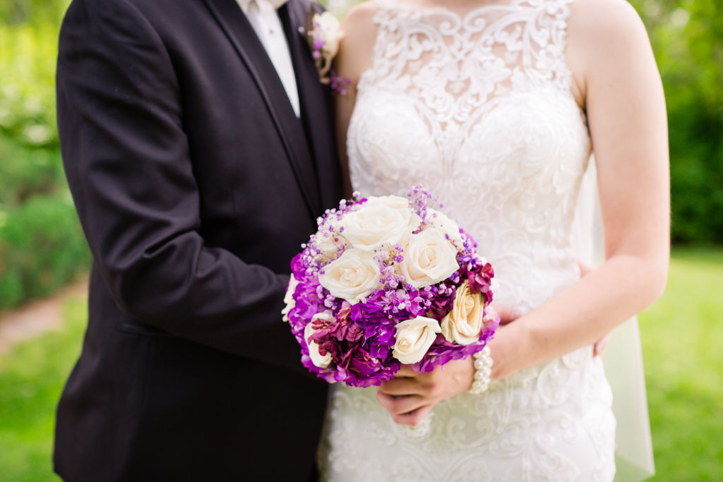 close up of bride holding bouquet and groom embracing her