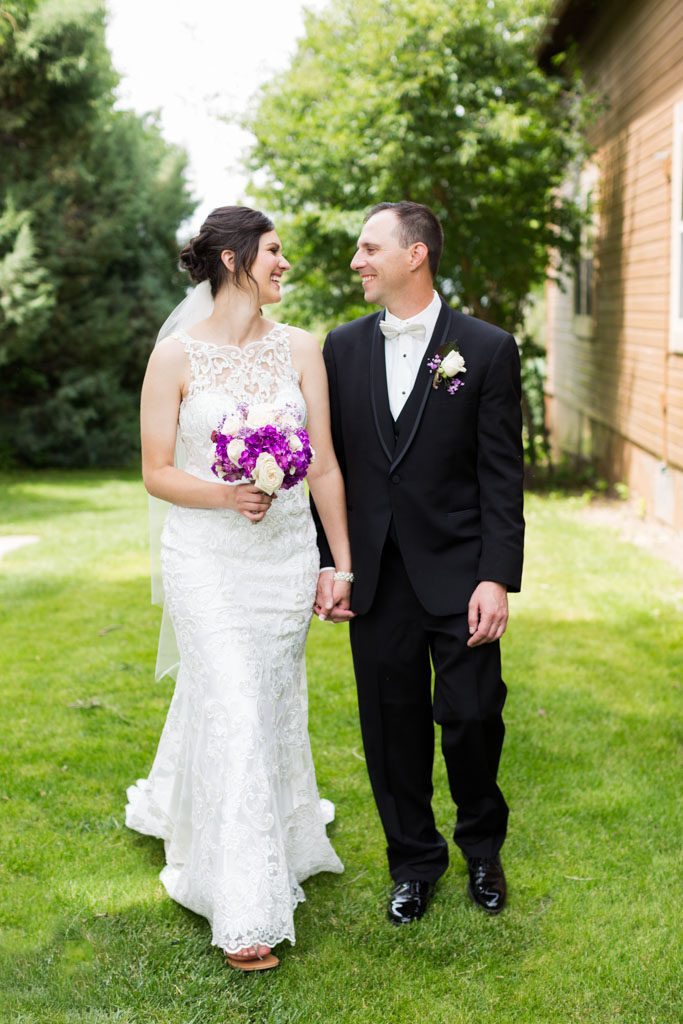 bride and groom smile as they walk on lawn