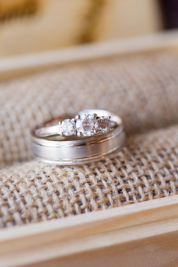 wedding rings gently stacked on the burlap lining of a wooden ring box