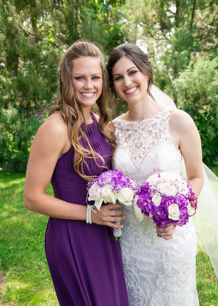 Bride poses with bridesmaid in purple dress