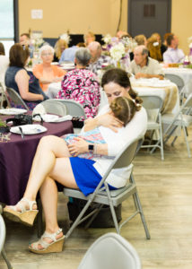mom snuggles her daughter during reception