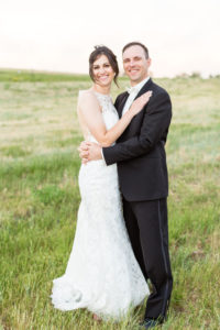 bride and groom smile in field during wedding reception