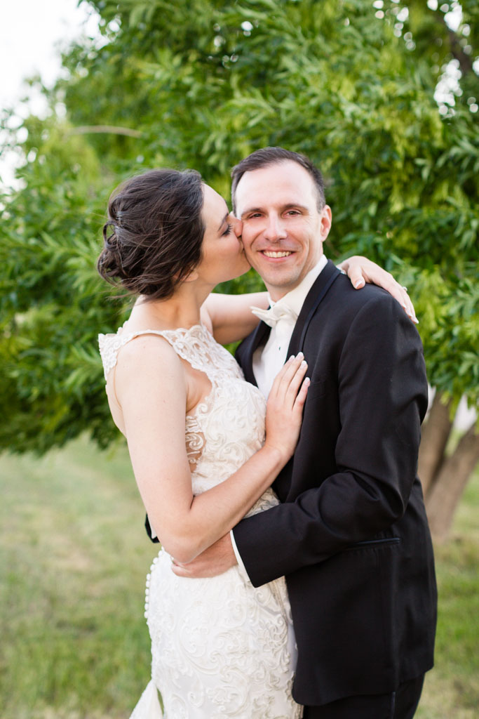 bride and groom kiss near a tree